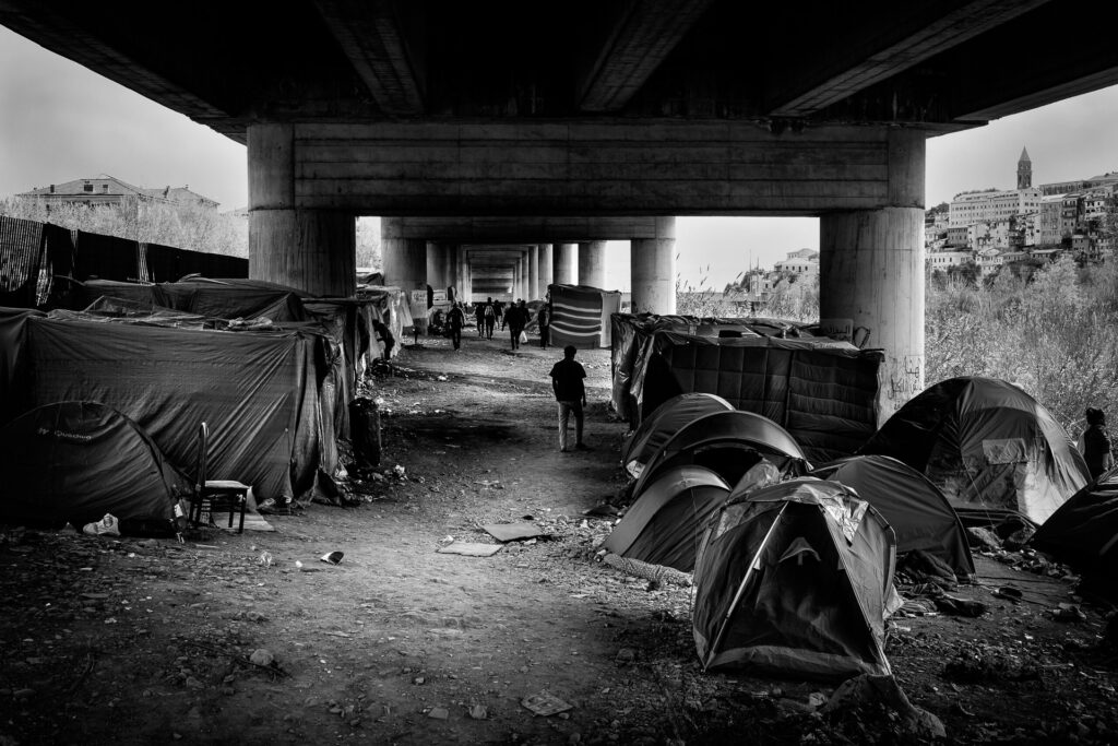 Each time I return, the camp under the highway viaduct on the banks of the Roja River is different.