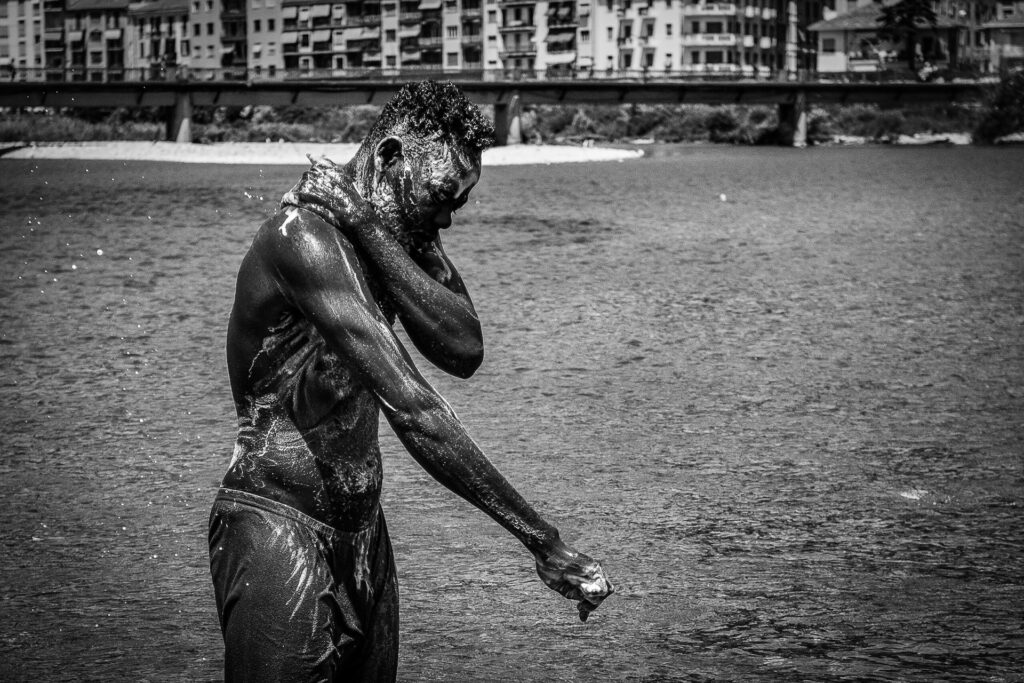 A Sudanese boy washes himself at the mouth of the Roja River. Ventimiglia, 2020.