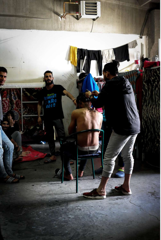 Inside the camps, people organize themselves as best they can, trying to earn some money to continue their journey, using whatever skills they have—such as working as barbers—or other informal means. Their legal status in Bosnia is undefined, and they are not allowed to work while waiting to move on. Miral Camp, Velika Kladuša, Bosnia and Herzegovina, 2019.