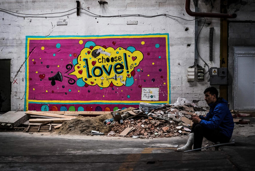 A mural made by a humanitarian organization in Bira Camp reads: “Choose love.” Choose it when you are pushed back for the twentieth time. Choose it when you realize you are confined outside the borders of the EU. Love your guards—they are ordering you to. Ignore the war in your head. Ignore the pain in your legs. Choose love. Bira refugees camp, Bihac, Bosnia Herzegovina, 2019.