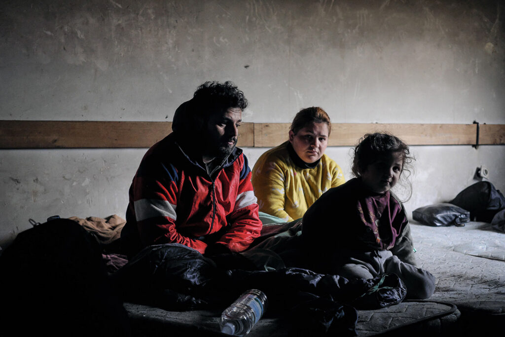 An abandoned shelter in the woods provides refuge for around twenty people, as many others before them, judging by the condition of the structure. Amid the rubbish, entire families, an elderly man alone, and a pregnant woman. Water is their most precious resource. Somewhere between Bosnia and Herzegovina and Croatia, 2019.