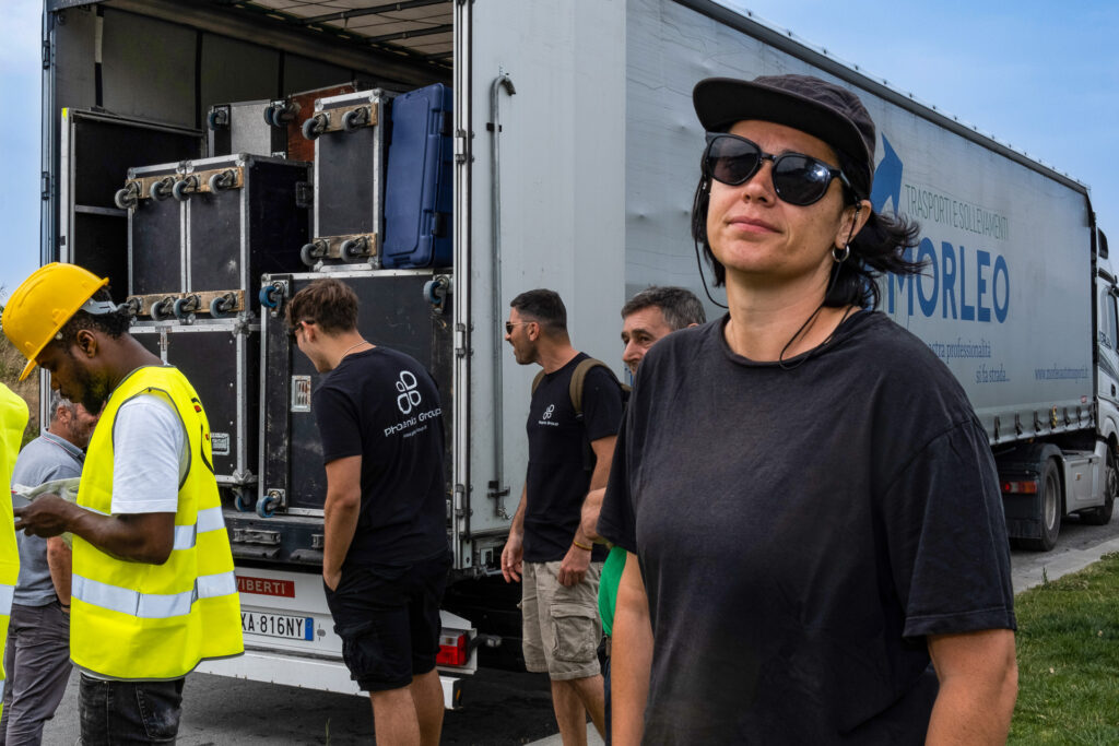 Francesca, a production manager, supervises stagehands and technicians unloading a truck full of audio and lighting equipment at the beginning of the stage setup. During the rest of the year, she works in a venue in Genoa’s city centre. Genoa, June 22nd 2022.