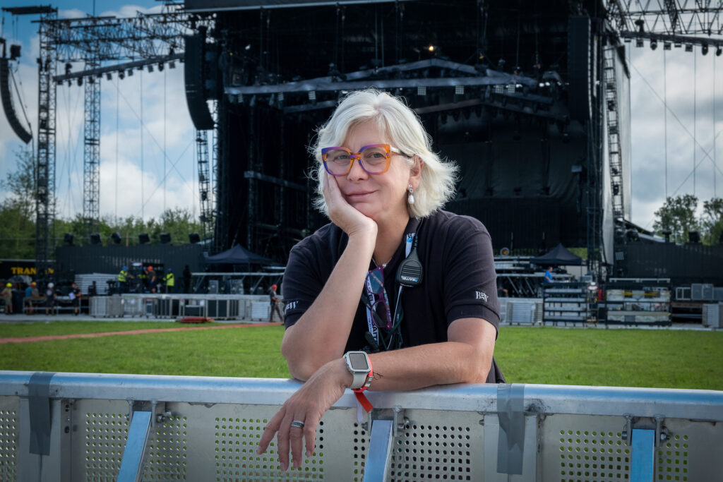Elisabetta, safety coordinator, poses in front of one of the stages she is responsible for. Her role is to ensure safety compliance for everyone working on site, including technicians, stagehands, artists, musicians and the audience. Ferrara, August 20th 2023.