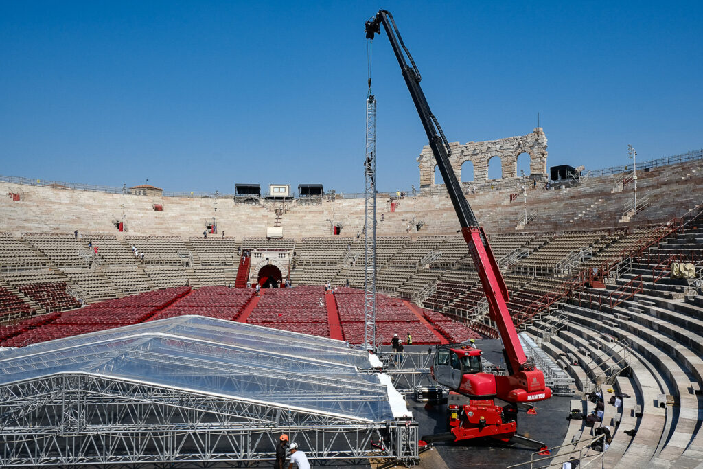 A crane lifts one of the antennas of the Space Roof structure during the setup of the stage inside the Arena di Verona. The transparent crystal roof allows the ancient Roman amphitheatre to remain visible even during large-scale live productions. Arena di Verona, July 25th 2022.