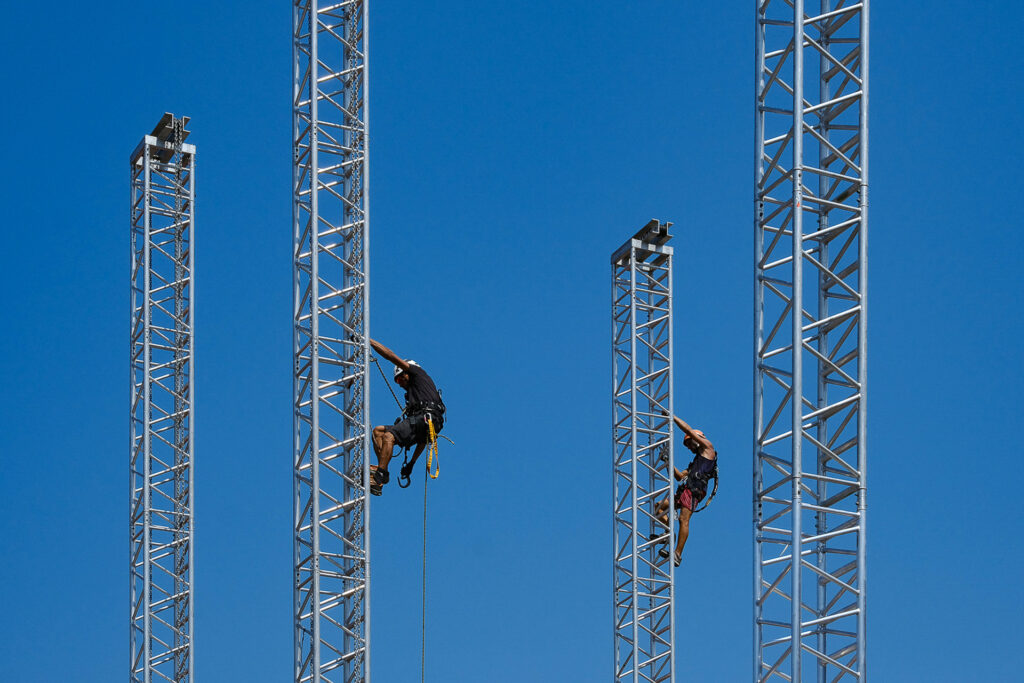 Two riggers climb the antennas of the Space Roof structure in order to secure the motors that will lift the stage roof into position. Arena di Verona, July 25th 2022.