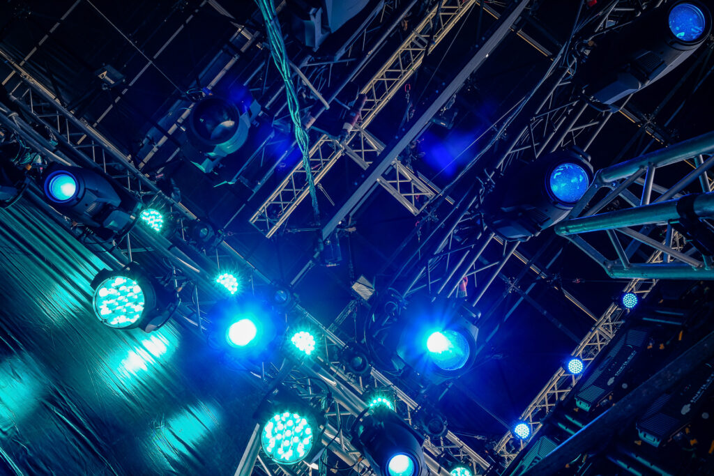 Lighting fixtures and truss structures during the setup and testing of a concert stage. Before the audience arrives, every beam, color and movement is programmed and rehearsed to shape the visual identity of the live show. Rome, April 2023.