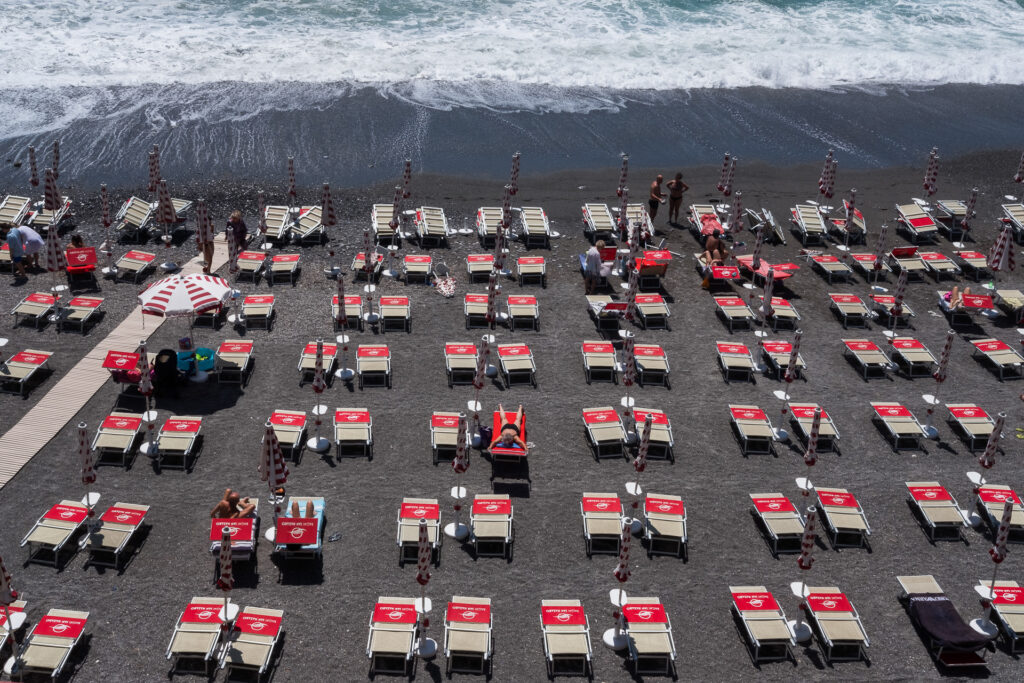 View of the San Nazaro bathing establishment, where rows of umbrellas and sunbeds appear almost unchanged despite the Covid-19 pandemic. Unlike public beaches, where access and distancing were directly regulated and monitored, safety management inside bathing establishments was delegated to private operators. Although San Nazaro is managed through a publicly participated company, access to the facility remains paid for citizens, reflecting the broader division between free public beaches and privately managed establishments along the Ligurian coast.