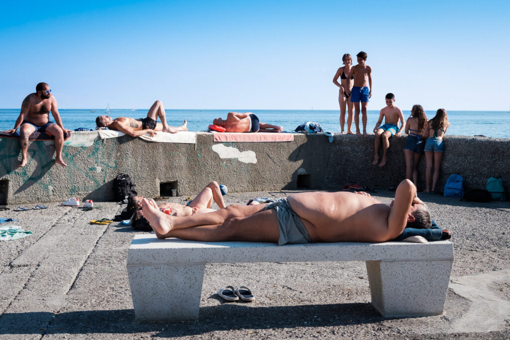 People sunbathing on a public terrace in the Quinto district. Because of the limited availability of free public beaches, many people usually gather on terraces, piers and rocky shorelines — spaces which, at the time, also remained outside Covid-19 regulations. Genoa, June 2nd 2020.