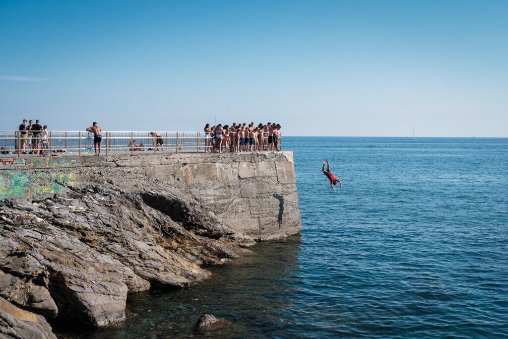 Now dedicated to Gianluca Vialli, a beloved Italian football player, the “Molo dell’Amicizia” extends over the rocks protecting the small public beach beside the gardens of Quinto. Here, even a small group of boys diving from the pier appears — and is perceived — as a crowd.. Genoa, June 2nd 2020.